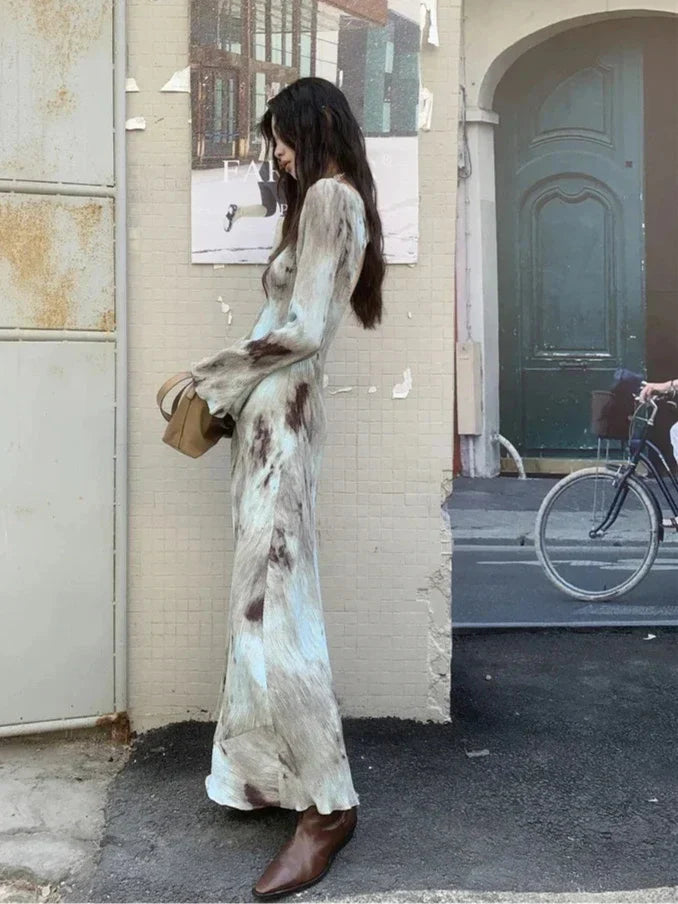 Side view of a woman in a tie-dye maxi dress, showcasing the flowing silhouette and flared cuffs.