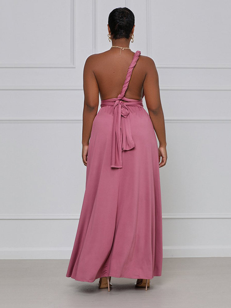 Back view of a woman wearing a dusty rose maxi dress styled as a one-shoulder with a tie detail.