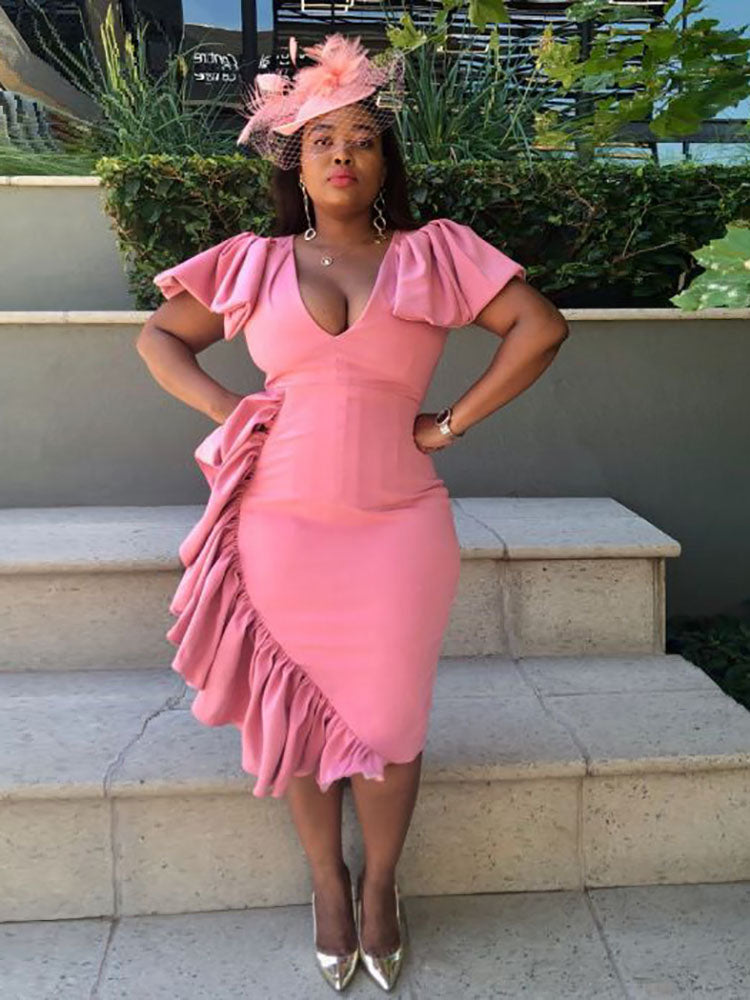 woman in a pink ruffled dress with a fascinator on stairs