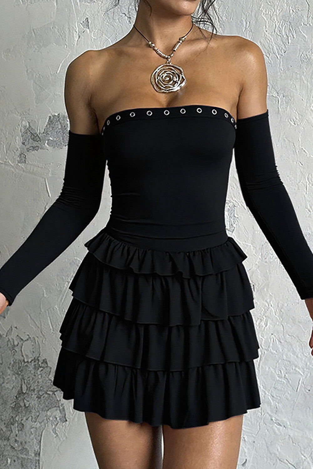 Model wearing a black off-the-shoulder dress with long sleeves and a ruffled skirt.