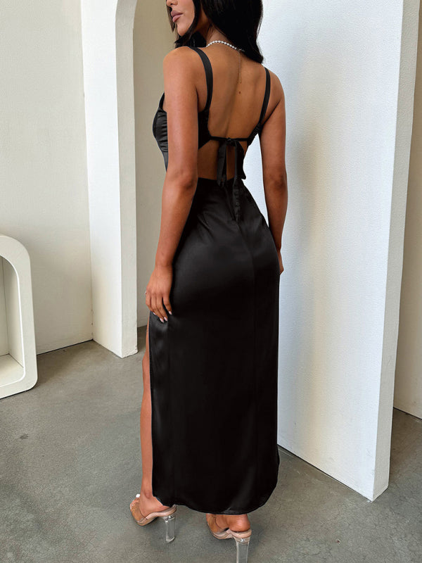 Rear view of a woman in a long black satin dress with an open back and tie closure, featuring a high leg slit.