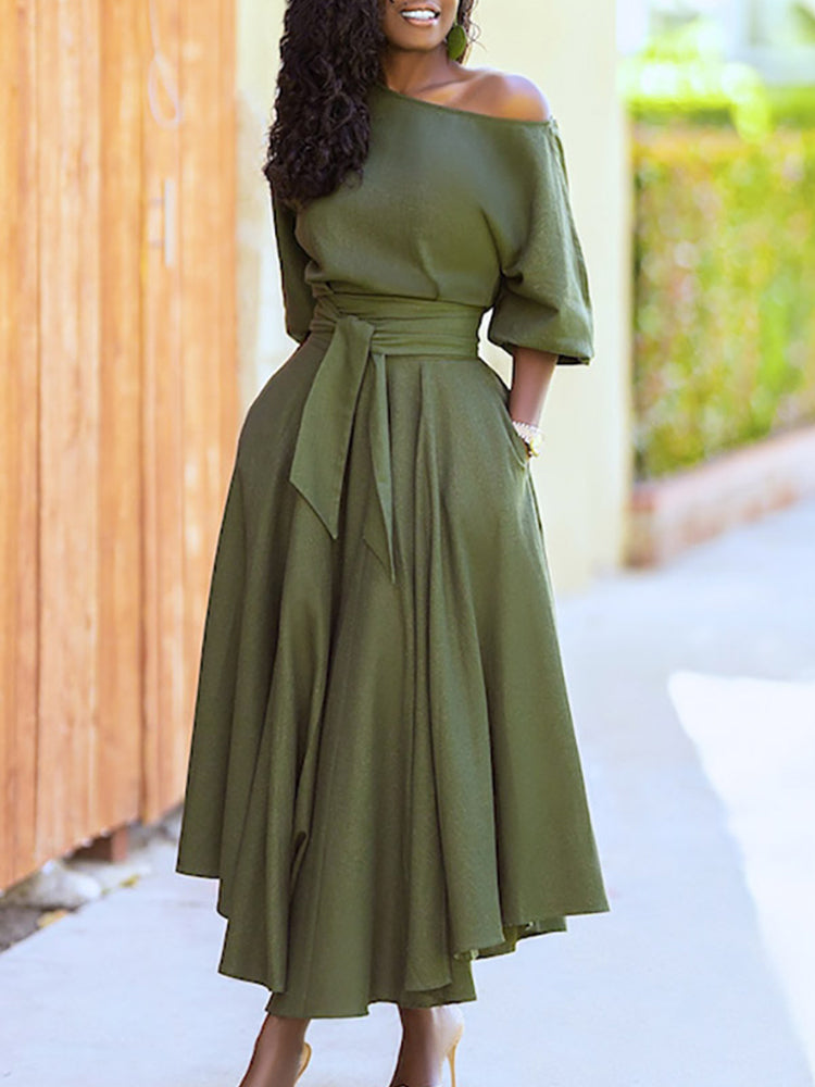 Full body shot of a woman in a green belted midi dress