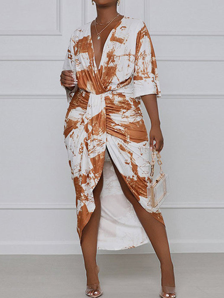Front view of a woman wearing a brown and white tie-dye print wrap dress, holding a clear handbag.