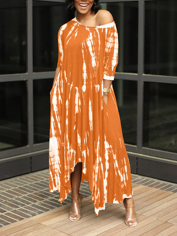 Woman wearing an orange tie-dye maxi dress with an asymmetrical hem and three-quarter sleeves, standing outdoors.