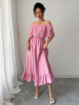 Woman wearing a pink off-the-shoulder maxi dress with lace bodice and ruffled hem, front view