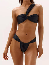 Woman wearing a black one-shoulder bikini with twisted bust and high-cut bottoms.