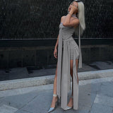 Woman in a grey strapless dress with draped fabric, posing with her hand near her face.