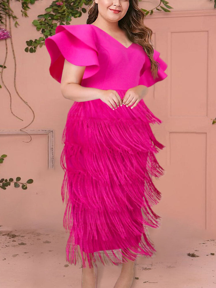 Plus-size woman modeling a hot pink dress featuring layered fringe and ruffled sleeves, against a pale pink wall.