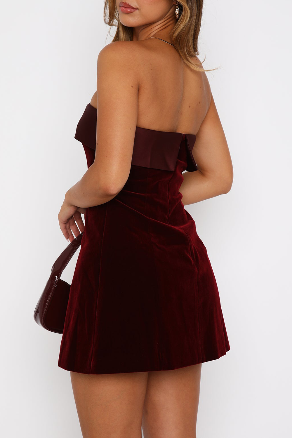 Back view of a woman in a burgundy velvet strapless mini dress
