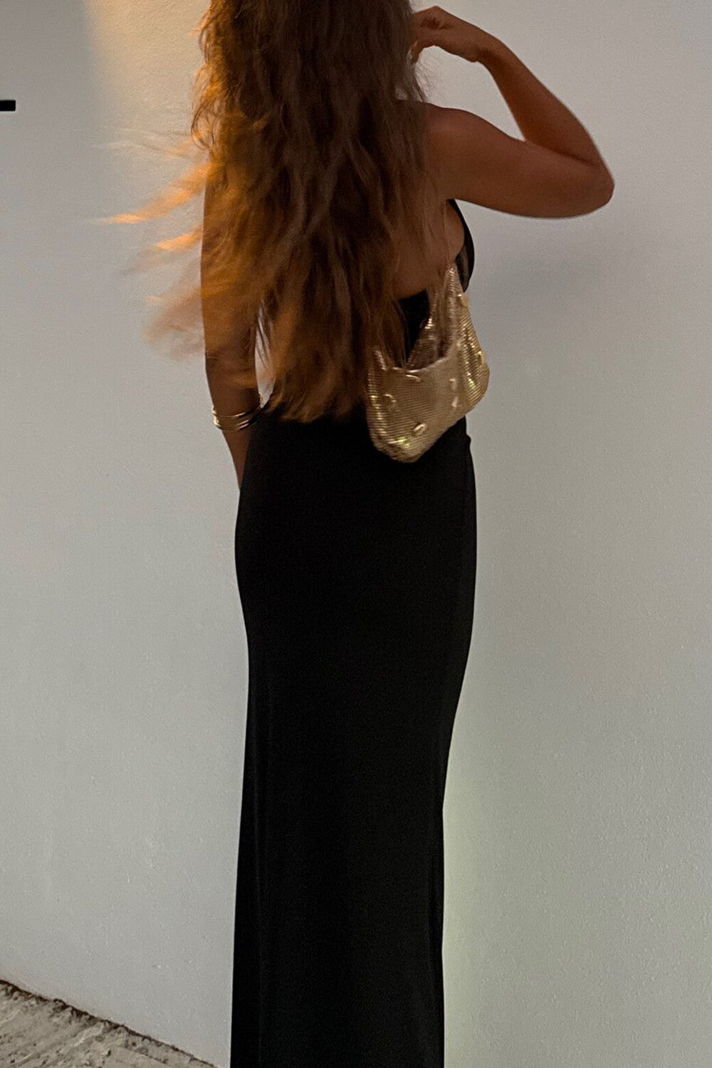 Back view of a woman in a black maxi dress with long, flowing hair