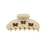 Close-up of a cream claw clip featuring decorative brown bows