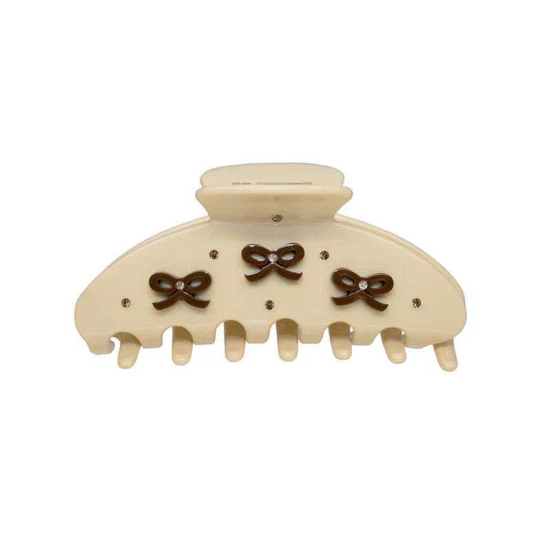 Close-up of a cream claw clip featuring decorative brown bows