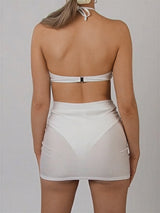 back view of a woman wearing a white halter neck bandeau bikini top with a clasp closure and a sheer mini skirt