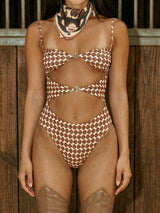 Front view of a woman wearing a geometric print one-piece swimsuit with cutouts and gold hardware.
