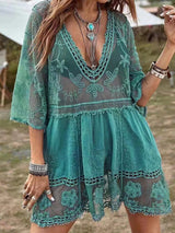 Woman wearing a teal lace cover-up with a V-neckline and tiered skirt.