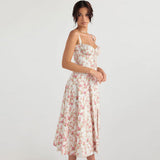 Side profile of a woman wearing a white floral print midi dress with a sweetheart neckline and spaghetti straps.