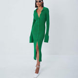 Woman wearing a long-sleeved green ribbed knit midi dress with a collared neckline and a high slit, paired with white pointed-toe heels and sunglasses.