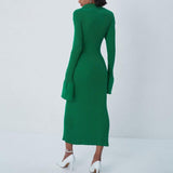 Back view of a woman in a long-sleeved green ribbed knit midi dress with a collared neckline and a high slit.