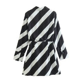 Back view of a black and white striped long-sleeved mini dress with a pointed collar and wrap-style front, laid flat.