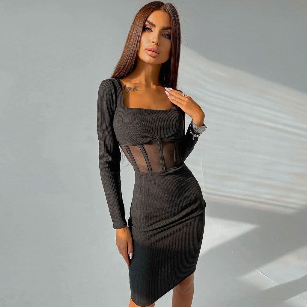 Front view of a woman in a black long-sleeved ribbed knit dress with sheer mesh waist detailing and a square neckline.