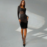 Full-body shot of a woman wearing a black long-sleeved ribbed knit dress with sheer mesh waist detailing and a square neckline, paired with black pointed-toe heels.