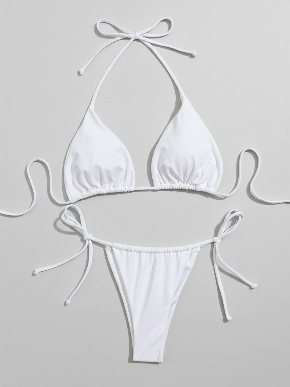 White halterneck bikini top and tie-side bottoms laid flat, front view.