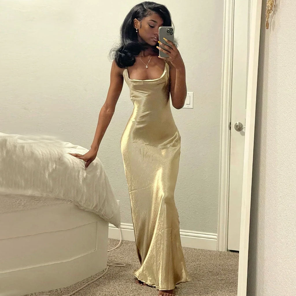 Woman in a gold satin slip dress taking a selfie in a mirror