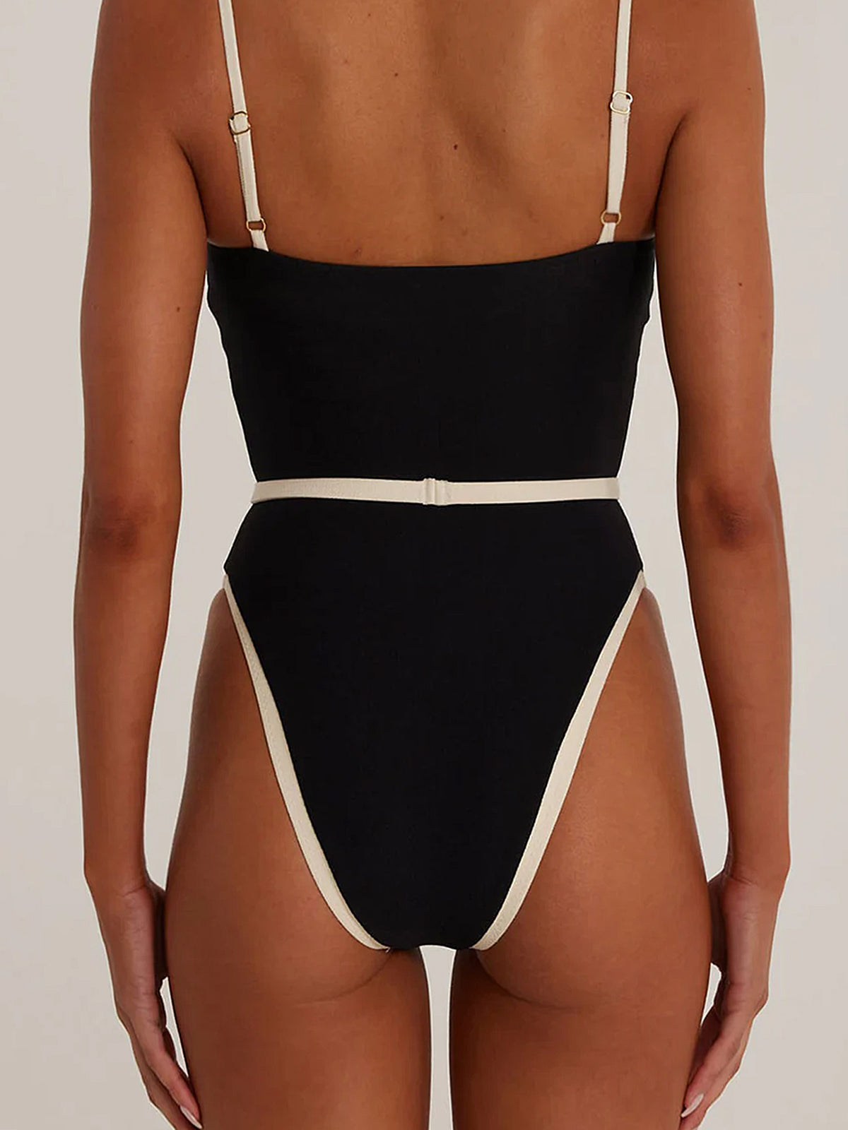 Back view of a black one-piece swimsuit with contrast trim and high-cut legs.
