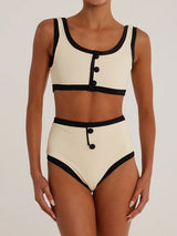 Woman wearing a cream and black ribbed bikini set, front view.