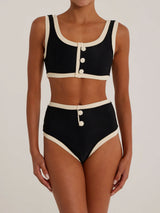 Woman wearing a black and cream ribbed bikini set, front view.