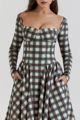 Front view of a woman wearing a long-sleeved plaid dress with a fitted bodice and full skirt.