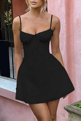 Woman wearing a black mini dress with spaghetti straps and a sweetheart neckline.