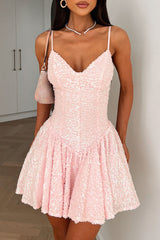 Woman wearing a pink sequined mini dress with spaghetti straps and a v-neckline.