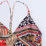 Close-up of the v-neckline and spaghetti straps of a patchwork print maxi dress, showing intricate pattern details.