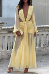 Yellow floor-length dress with a deep V-neck, cut-out waist, and flowing skirt, held by a woman outdoors.