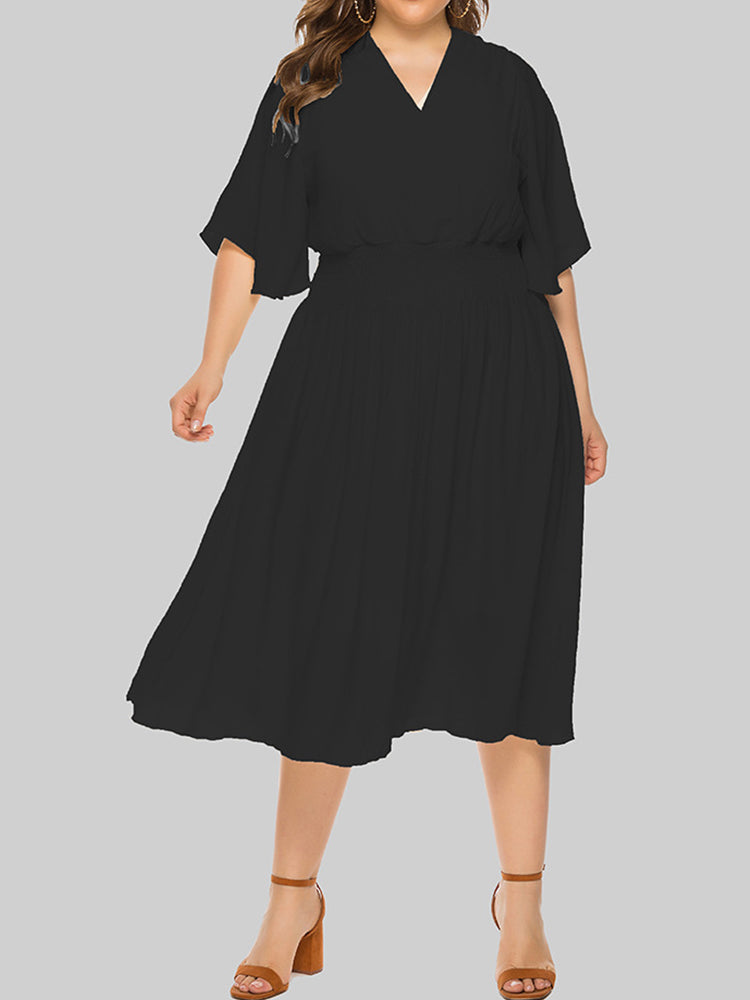 Plus-size woman wearing a black midi dress with flutter sleeves and a smocked waist, shown from the front.