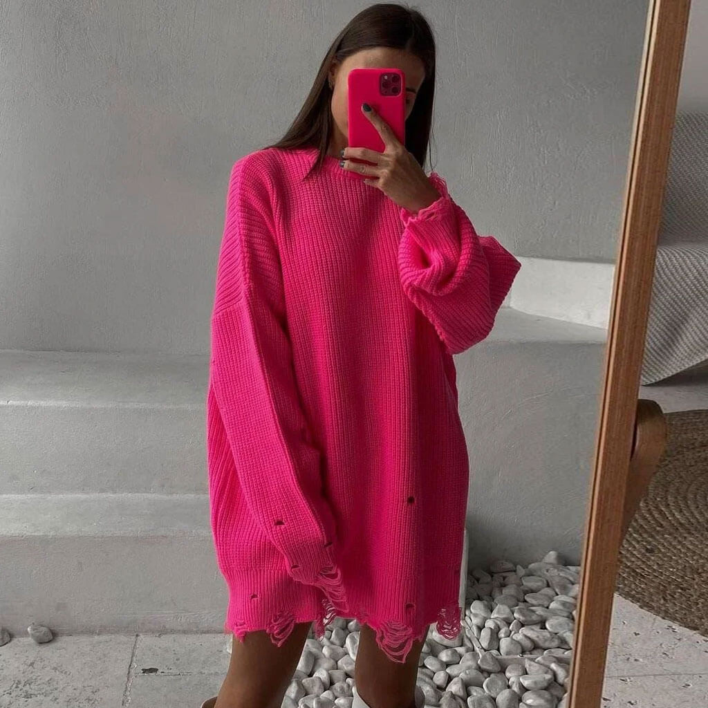 Woman taking a mirror selfie in a bright pink oversized distressed knit sweater dress