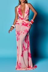 woman wearing a light pink and magenta tie-dye maxi dress with a plunging neckline and cut-out sides
