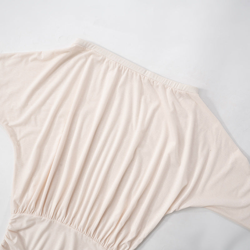 Close-up of the draped dolman sleeve and ruched waist of the off-the-shoulder mini dress.
