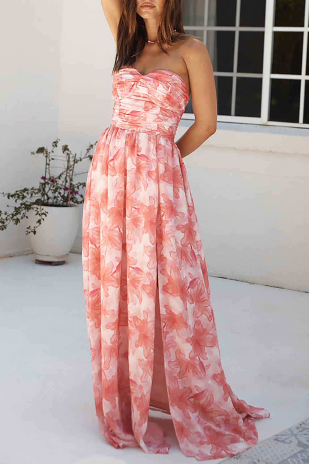 Full body shot of a woman in a strapless floral print maxi dress with a high slit