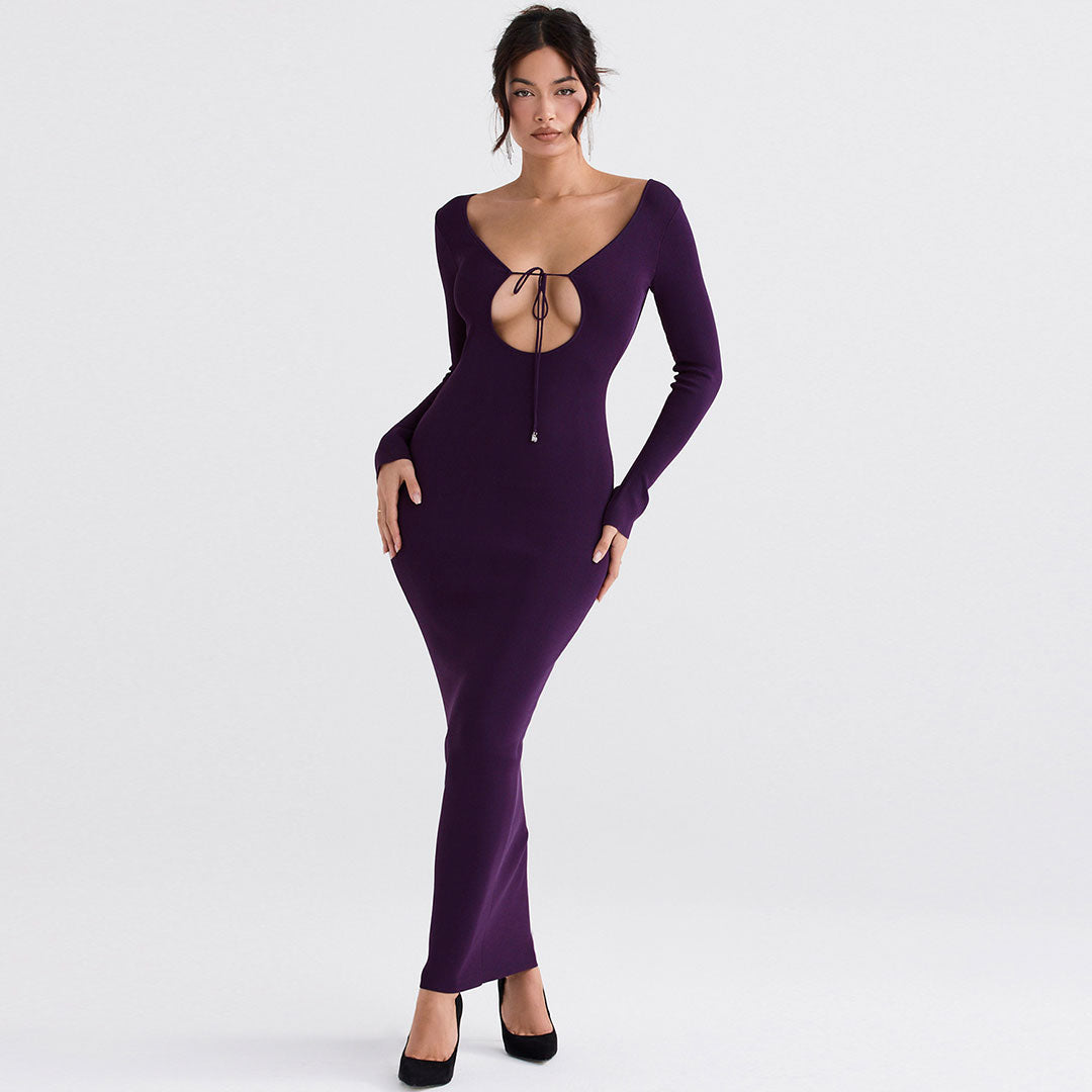 Woman wearing a long purple dress with a plunging neckline and long sleeves, standing against a white background.