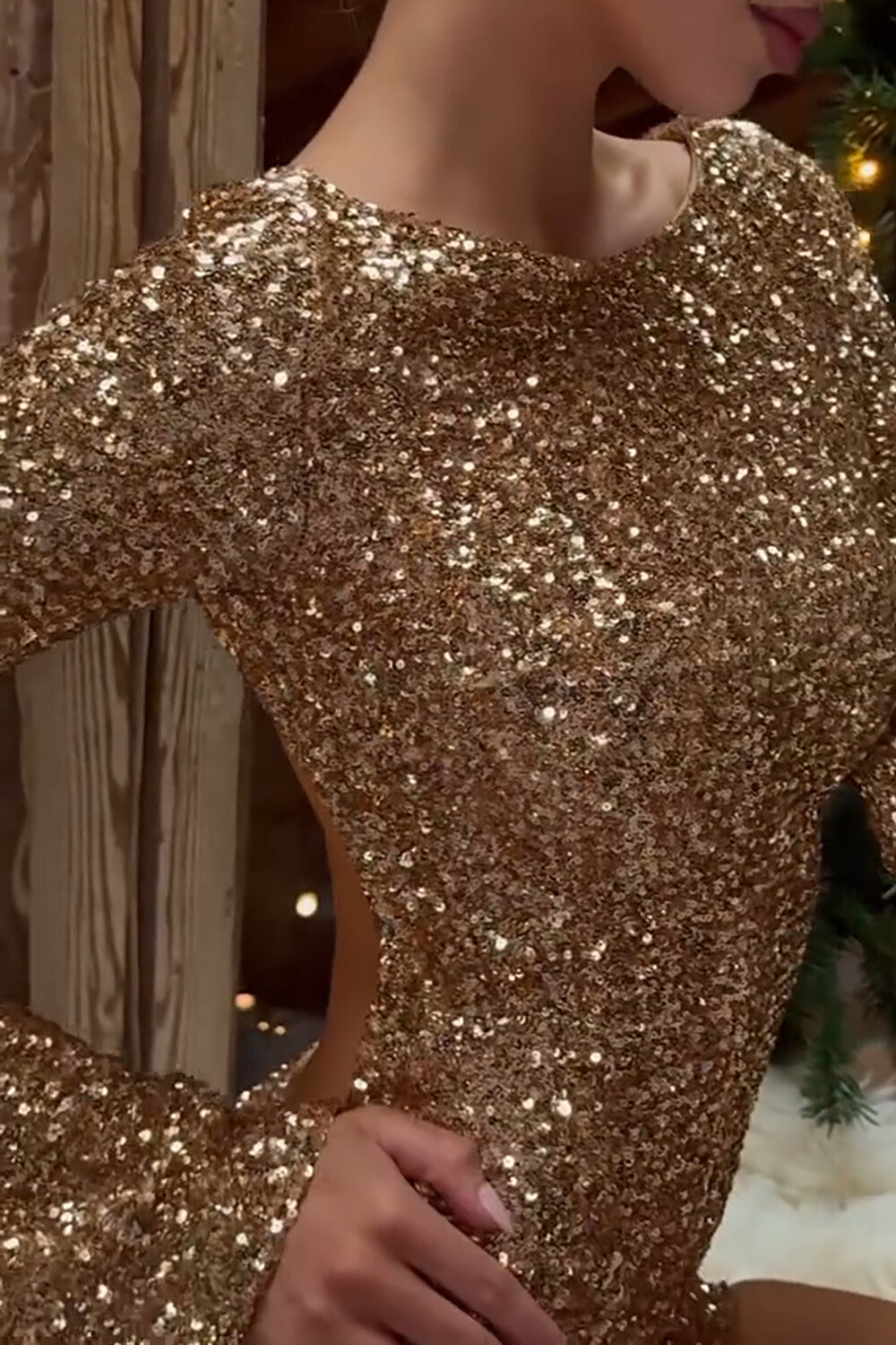Close-up of the front of a woman wearing a gold sequined long-sleeved mini dress, highlighting the fabric texture and neckline.