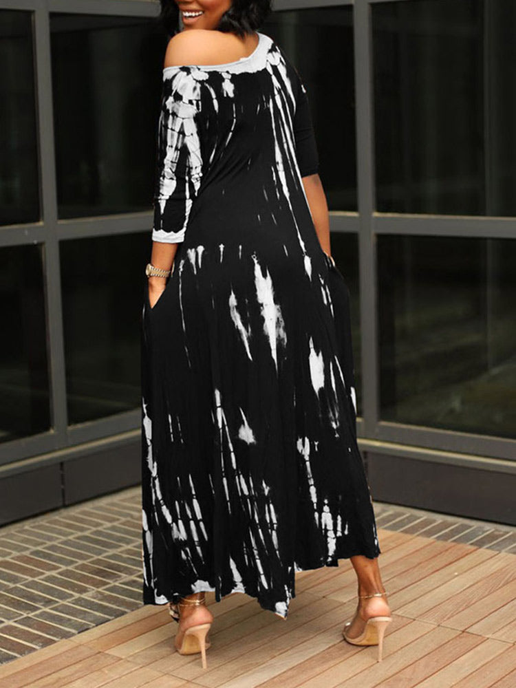 Back view of a woman wearing a black and white tie-dye maxi dress with an asymmetrical hem and pockets.