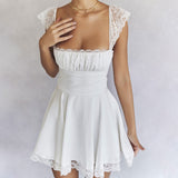 Close-up of a woman wearing a white mini dress with lace trim and a gold necklace