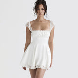 Woman wearing a white mini dress with lace trim against a white background