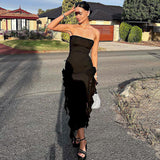 woman wearing a black strapless midi dress with ruffled hem and high slit