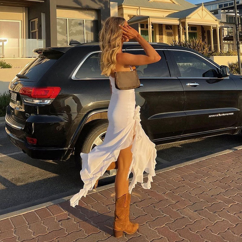 woman in a white flowing dress with a thigh-high slit and ruffled trim