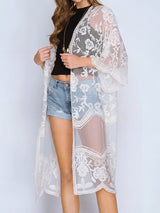 woman wearing a white lace kimono over a black top and denim shorts