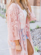 woman wearing a pink lace kimono over a white tank top and denim shorts