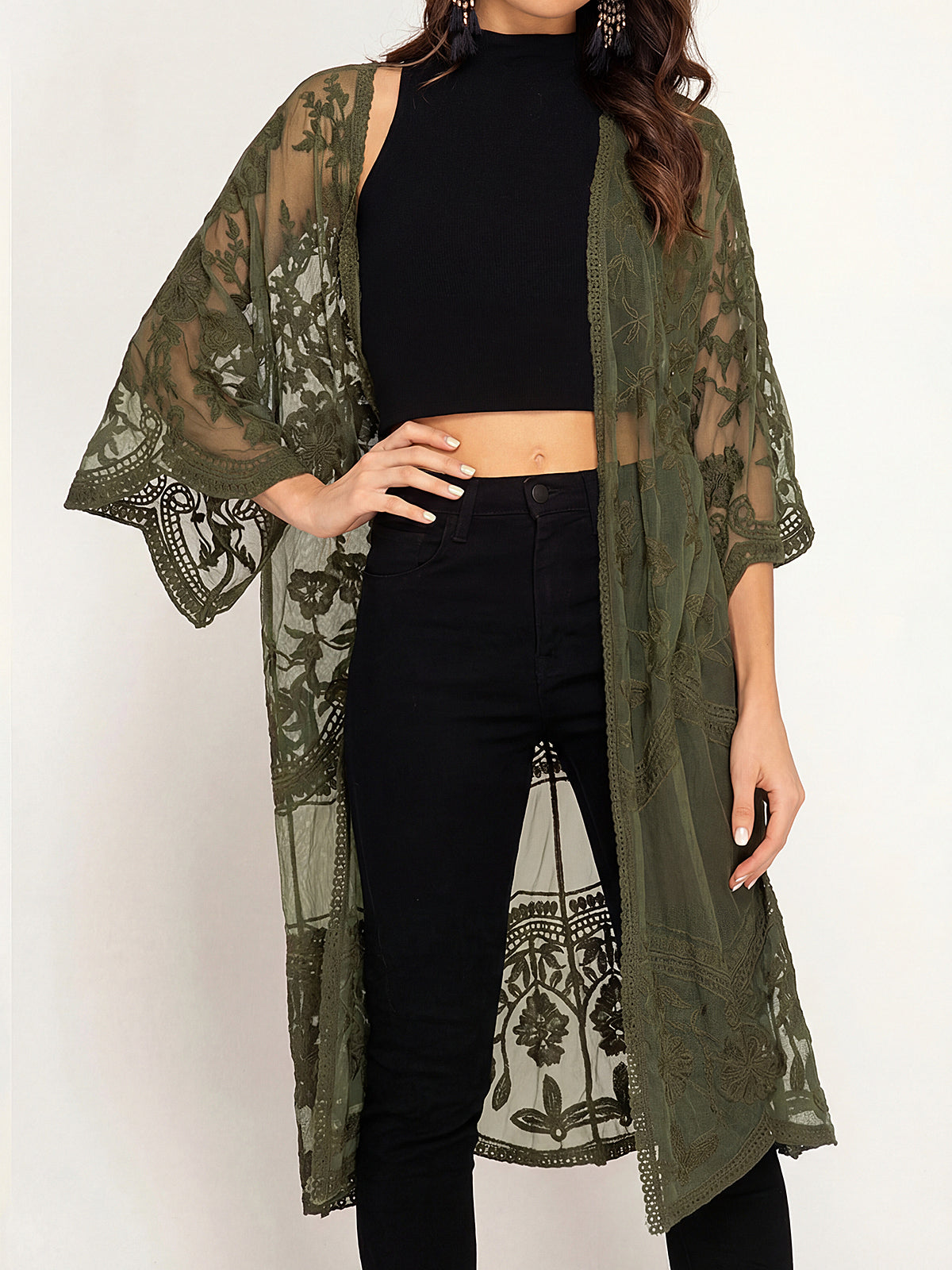 woman wearing an olive green lace kimono over a black crop top and black pants